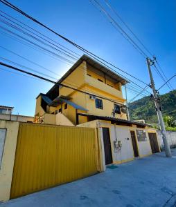 una casa amarilla con una valla delante de ella en Pousada Village Rio Centro, en Río de Janeiro