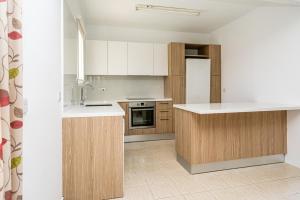 a kitchen with wooden cabinets and a white refrigerator at Kotsias Corallia Villas in Coral Bay