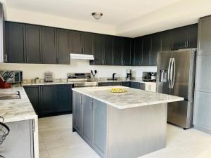 a kitchen with black cabinets and a stainless steel refrigerator at Luxury Mansion minutes to Niagara Falls and Buffalo in Port Colborne