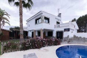 a white house with a swimming pool and palm trees at Villa en Valencia, metro, accesibilidad in La Eliana