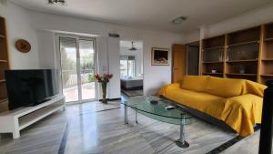 a living room with a yellow couch and a tv at Nian Apartments - by Avelink in Spáta