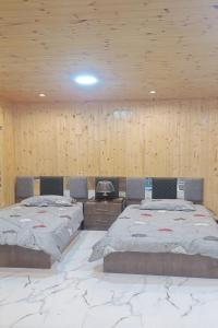 Duas camas num quarto com paredes de madeira em white tulips studio em Gérasa