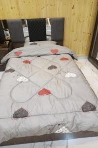 uma cama com um cobertor branco com flores vermelhas em white tulips studio em Gérasa