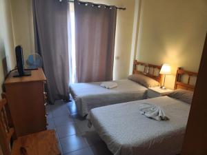 Cette chambre comprend deux lits et une télévision. dans l'établissement Vitamina Sea, à Puerto de Santiago