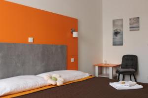 1 dormitorio con 1 cama con pared de color naranja en Apartments Verona Karlovy Vary, en Karlovy Vary