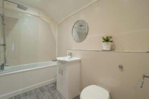 uma casa de banho com um WC, um lavatório e um espelho. em The Cartlodge em Higham