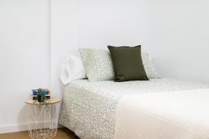 a white bedroom with a bed and a side table at Centro y Confort: Junto a Corte Inglés in Granada