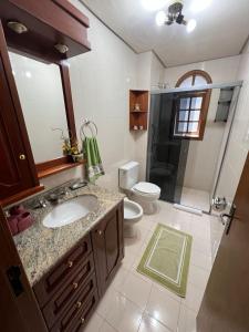 a bathroom with a sink and a toilet and a shower at Apartamento 4 dormitórios no coração de Gramado in Gramado