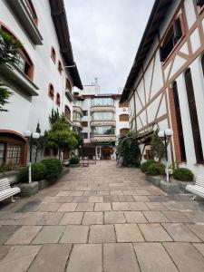 a courtyard of a building with two benches in front at Apartamento 4 dormitórios no coração de Gramado in Gramado