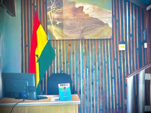 una oficina con escritorio, ordenador y bandera en Sylz Residence Studio 5 - 5 Mins from Labadi & Laboma Beaches, en Accra