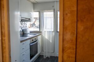 eine Küche mit weißen Schränken, einem Waschbecken und einem Fenster in der Unterkunft Habitación marinería Boat Aloha in Barcelona