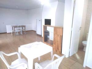 a room with a table and white chairs and a kitchen at Casa da tia Ju! in São José dos Pinhais