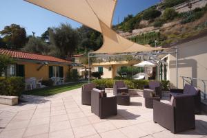un patio con un montón de sillas y una sombrilla en Residence Baia La Ruota, en Bordighera
