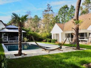 ein Haus mit einem Pool und zwei Palmen in der Unterkunft Villa avec piscine au coeur de la forêt in Le Touquet-Paris-Plage