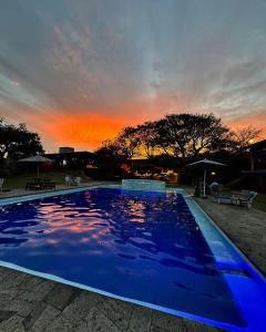 a large blue swimming pool with a sunset in the background at Los Cruxes Sam Paz in Tepoztlán