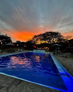 a large blue swimming pool with a sunset in the background at Los Cruxes in Tepoztlán
