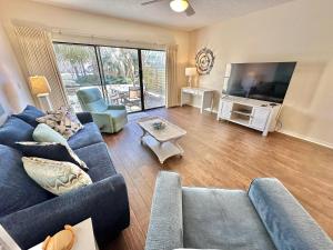 Una sala de estar con un sofá azul y un televisor de pantalla plana. en 5177 Beachwalk, en Destin