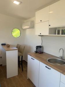 a kitchen with white cabinets and a sink and a table at Glamping nature Tiny house in Kotor