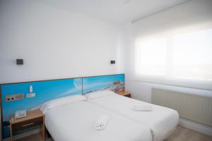 a bedroom with a large white bed with a blue headboard at Restaurante Hotel Abadesa in Villagonzalo-Pedernales