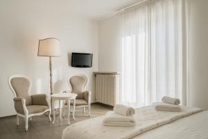 een witte slaapkamer met een bed en een tafel en stoelen bij Villa Telli in Garda