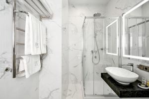 a white bathroom with a sink and a shower at BonApart Maidan by UHM in Kyiv