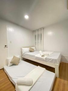 Duas camas num quarto com paredes brancas em REGIE Homestay Vigan City em Aggay
