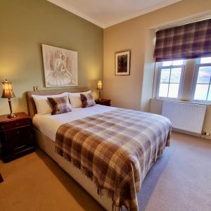 a bedroom with a bed with a plaid blanket at Loch Maree Hotel in Talladale