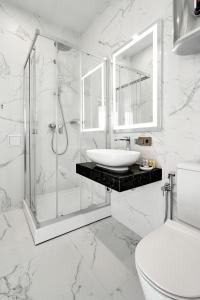 a white bathroom with a shower and a sink at BonApart Maidan by UHM in Kyiv