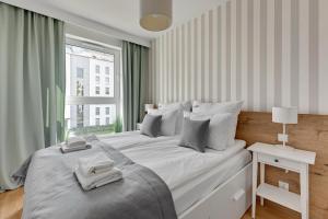 una camera da letto bianca con un letto grande e una finestra di Langgarten Apartments by Little Heaven a Danzica