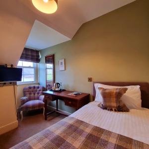 a bedroom with a bed and a desk and a chair at Loch Maree Hotel in Talladale