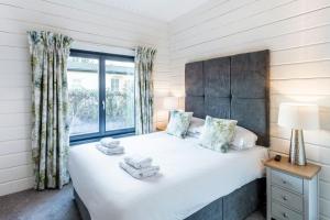 Un dormitorio con una cama grande y una ventana en Roydon Marina - Lodge 5 - Hot Tub, en Roydon