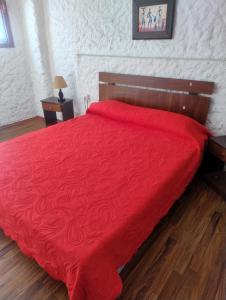 a bedroom with a red bed with a red blanket at Hotel Brisas del Quisco in El Quisco