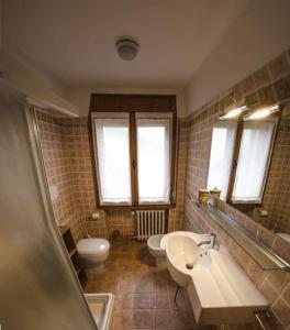 een badkamer met 2 wastafels, een toilet en ramen bij Villa Aurora in Pocol