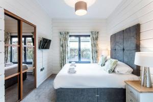 a bedroom with a large bed and a mirror at Roydon Marina - Lodge 4 - Hot Tub in Roydon