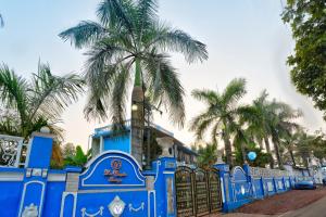 a blue fence with a palm tree behind it at Lacasita Villas & Cottages near Anjuna Beach & Shiva Valley in Anjuna