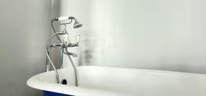 a bath tub with a shower in a bathroom at Santa Maria Hostel in Funchal