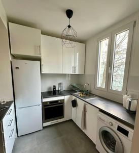een keuken met een witte koelkast en een vaatwasser bij Spacieux appartement calme 40m 2 in Parijs