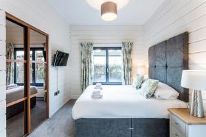 Roydon Marina - Lodge 8 - Hot Tub - Pet Friendly في Roydon: غرفة نوم بسرير كبير ومرآة