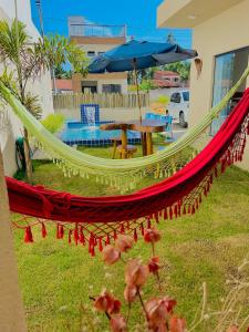 a hammock in a yard with a table and an umbrella at Casa Conchas do Patacho in Pôrto de Pedras