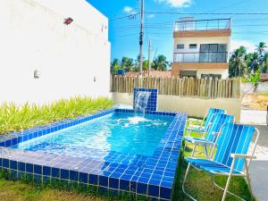 a swimming pool with blue chairs and a fountain at Casa Conchas do Patacho in Pôrto de Pedras