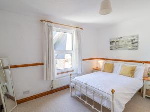 a bedroom with a white bed and a window at Lantern Cottage in Colyton