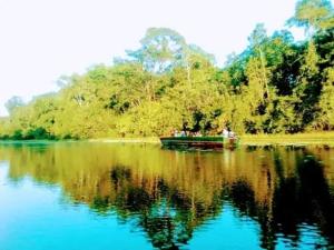 un barco en un lago con su reflejo en el agua en Bromelia Flower Lodge Iquitos, en Iquitos