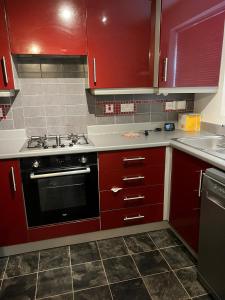 a kitchen with red cabinets and a black oven at Hevea Road House in Burton upon Trent