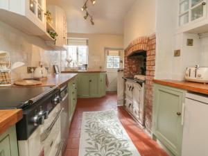 a kitchen with green cabinets and a brick oven at Stag Cottage in Minehead