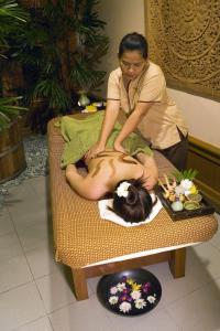a woman sitting on a table with a woman getting a massage at Bayview Hotel Langkawi in Kuah