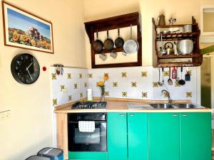 チェファルにあるCasa Giramondo by Housiliaのキッチン(緑のキャビネット、シンク、時計付)