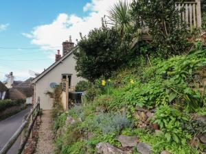 a cottage on a hill with flowers and plants at Stag Cottage in Minehead