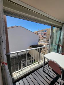 uma varanda com uma grande janela e uma mesa e cadeiras em Charmant appartement type T2 proche de la mer em Le Grau-du-Roi