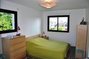 1 Schlafzimmer mit einem grünen Bett und 2 Fenstern in der Unterkunft Belle maison 3 étoiles avec vue mer lointaine depuis l'étage, à 400m à TREGASTEL - Réf 181 in Trégastel