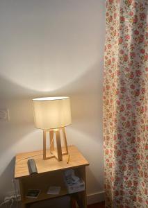 a lamp on a table next to a curtain at Chambre privé à deux pas de la gare in Montauban-de-Bretagne